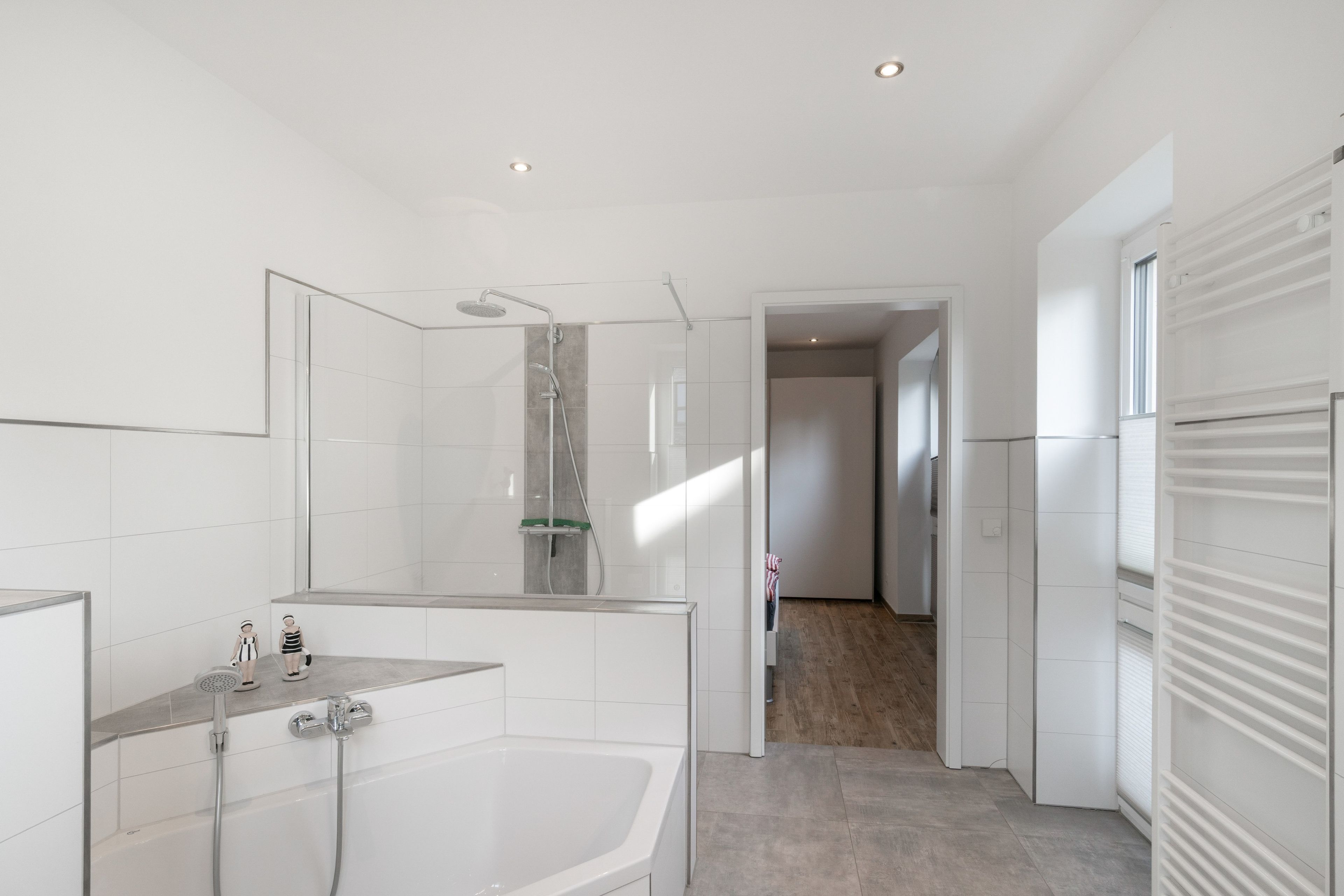 Ein modernes Badezimmer mit einer gläsernen Duschkabine, einer freistehenden Badewanne und einer begehbaren Dusche mit Glastür.
