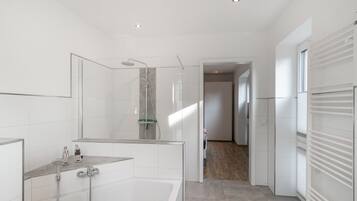 Ein modernes Badezimmer mit einer gläsernen Duschkabine, einer freistehenden Badewanne und einer begehbaren Dusche mit Glastür.