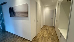Ein moderner Flur mit Holzboden, weißen Wänden und einem großen abstrakten Gemälde.