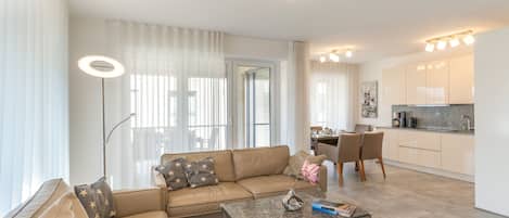 A modern living room with a sofa, coffee table, and a dining area with chairs.