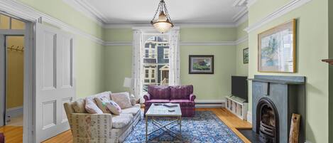 A living room with a fireplace, two sofas, a coffee table, and a patterned rug.