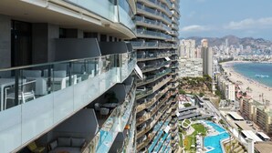 Un hotel moderno con múltiples balcones, una zona de piscina y vista a la playa.