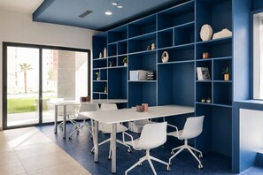 A modern meeting room with a white table, four white chairs, and a blue shelving unit with various items. - SUNSET SAILORS prestige apartment (Benidorm)
