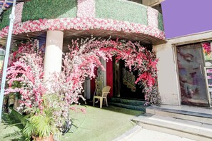 A building facade with a green and pink floral design, a red curtain, and a chair outside.