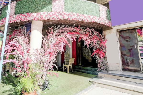 A building facade with a green and pink floral design, a red curtain, and a chair outside.