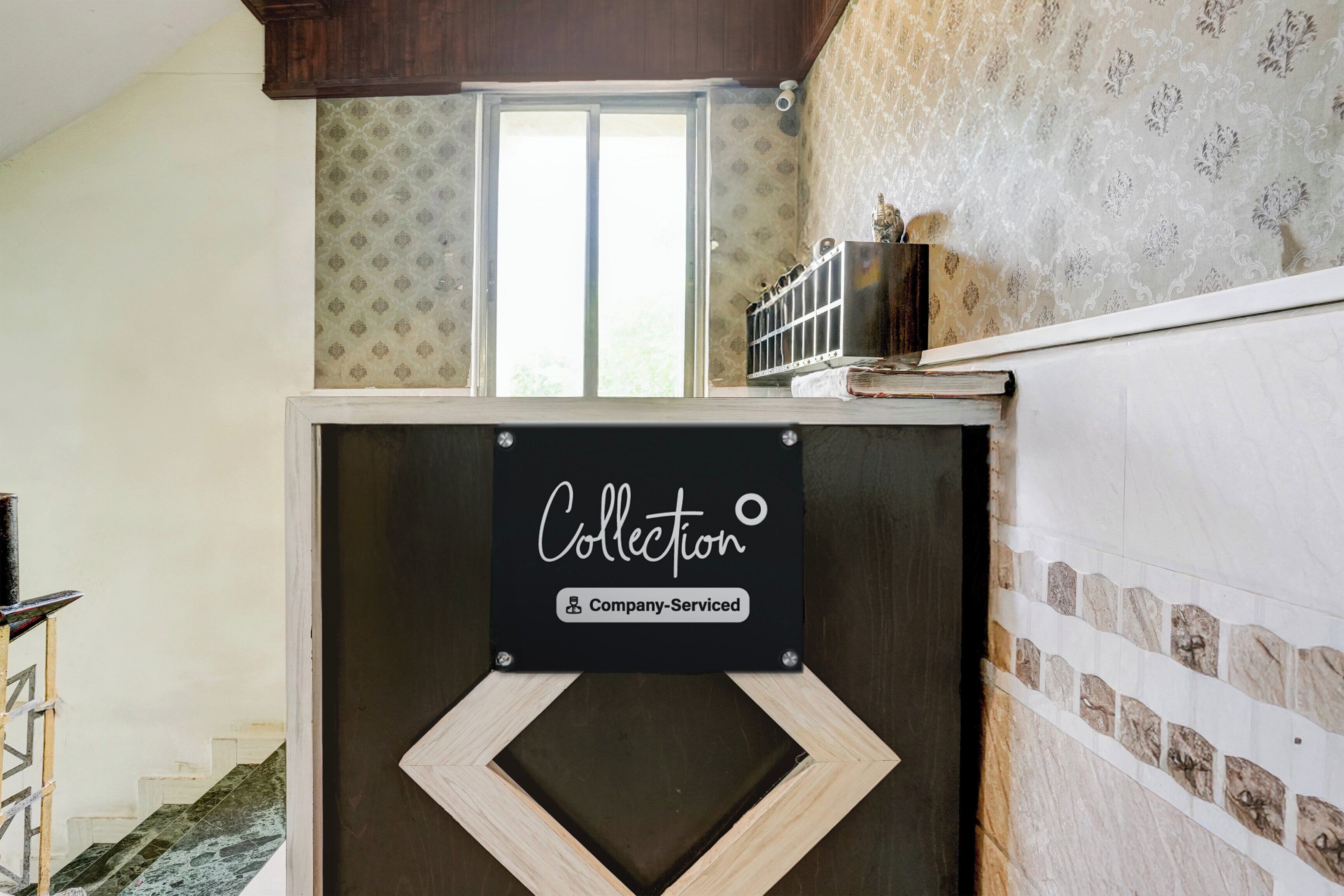 Een kamer met een raam, een decoratieve wand en een bord waarop 'Collector Company Serviced' staat.