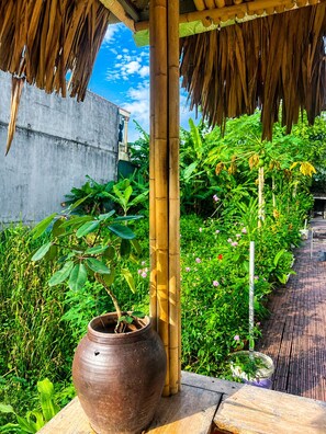 A garden with a bamboo structure, a large clay pot, and various tropical plants. - Tam Coc Sylvani Homestay (Nam Hoa Lu)