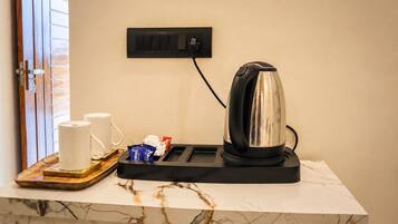 A marble countertop with a coffee maker, two white mugs, and a tray with packets.