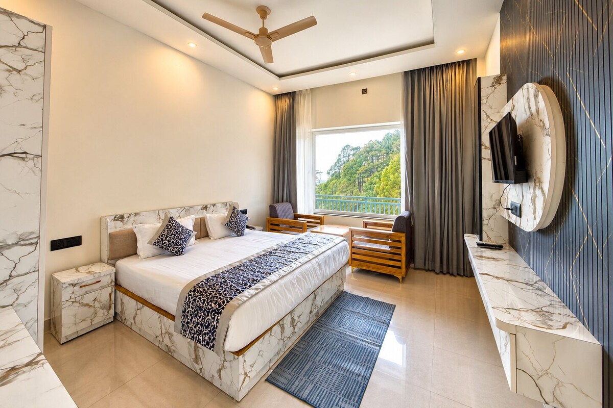 Un dormitorio moderno con cabecera de mármol, cama con ropa de cama estampada, un banco de madera, televisor montado en la pared y vista a zonas verdes.