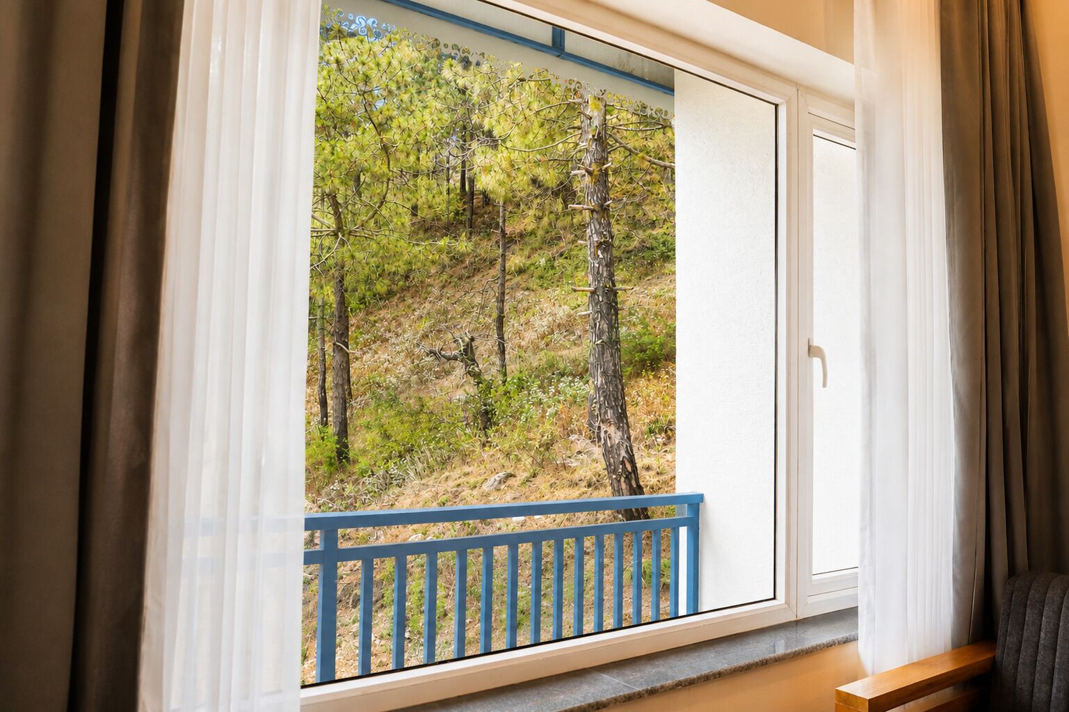 A room with a large window overlooking a forested area.