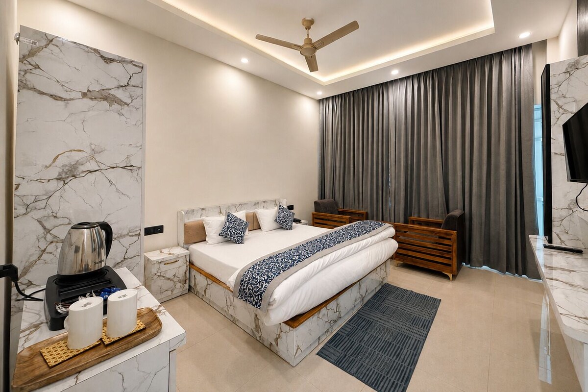 Un dormitorio moderno con cabecera de diseño de mármol, cama con ropa de cama estampada, mesita de noche con tetera y ventilador de techo.