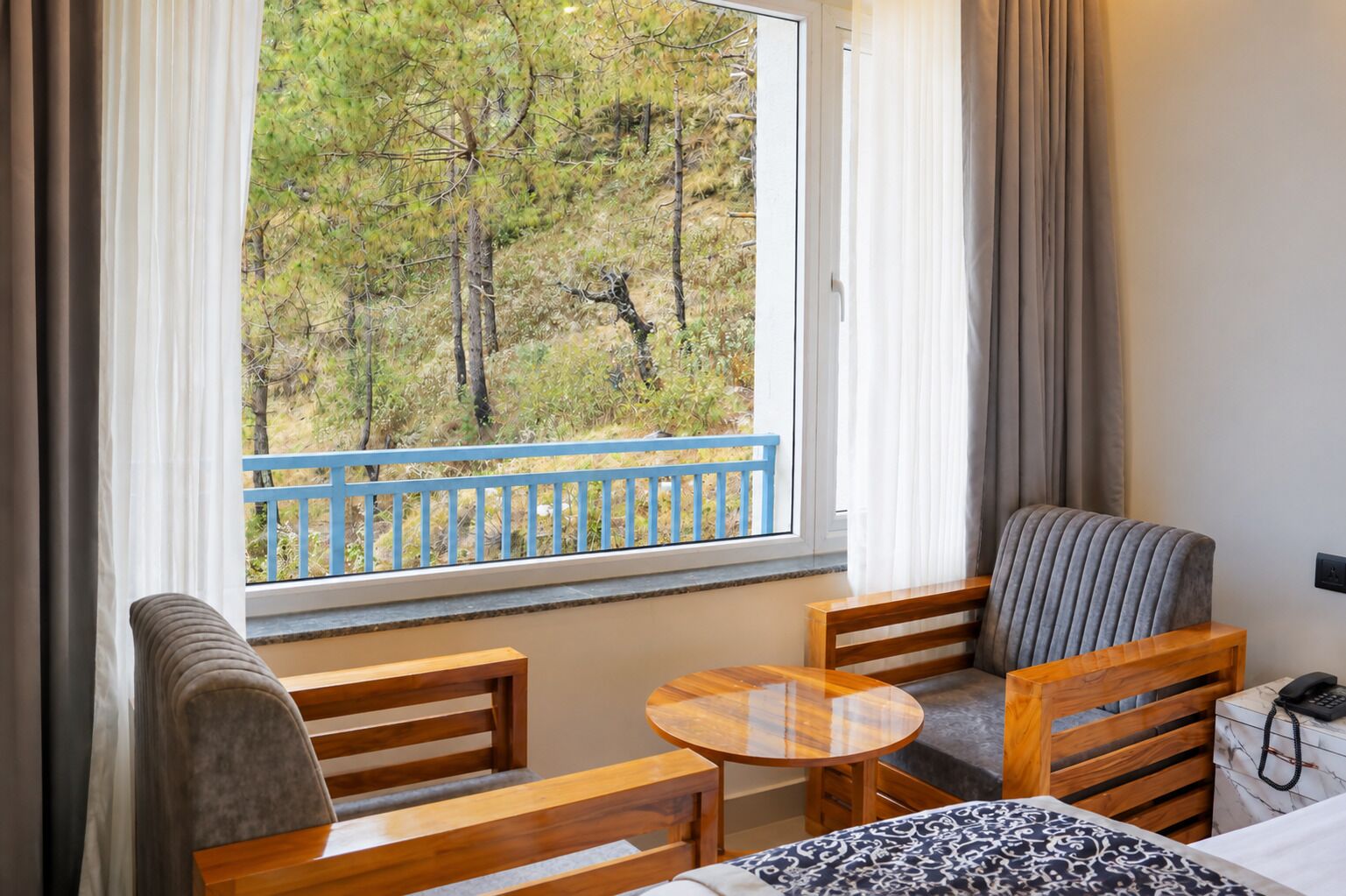 A room with a balcony, a bed, a small table, and a chair.