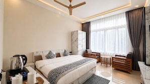 Een moderne hotelkamer met een groot bed, een zithoek, een koffiezetapparaat en een marmeren kast.