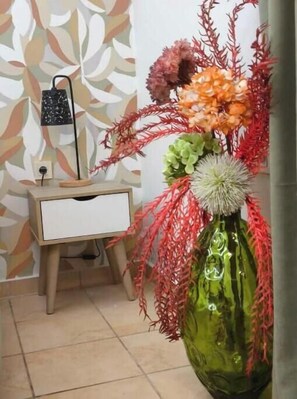 A green vase with flowers and red foliage on a table. - Voula's Apartment 1 (Chios)