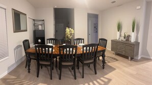 A dining area with a wooden table and black chairs, a dark door, and a grey cabinet with decorative items. - Spacious 5 bedroom in Haines city, Florida for families sleeping up to 12 guests (Haines City)