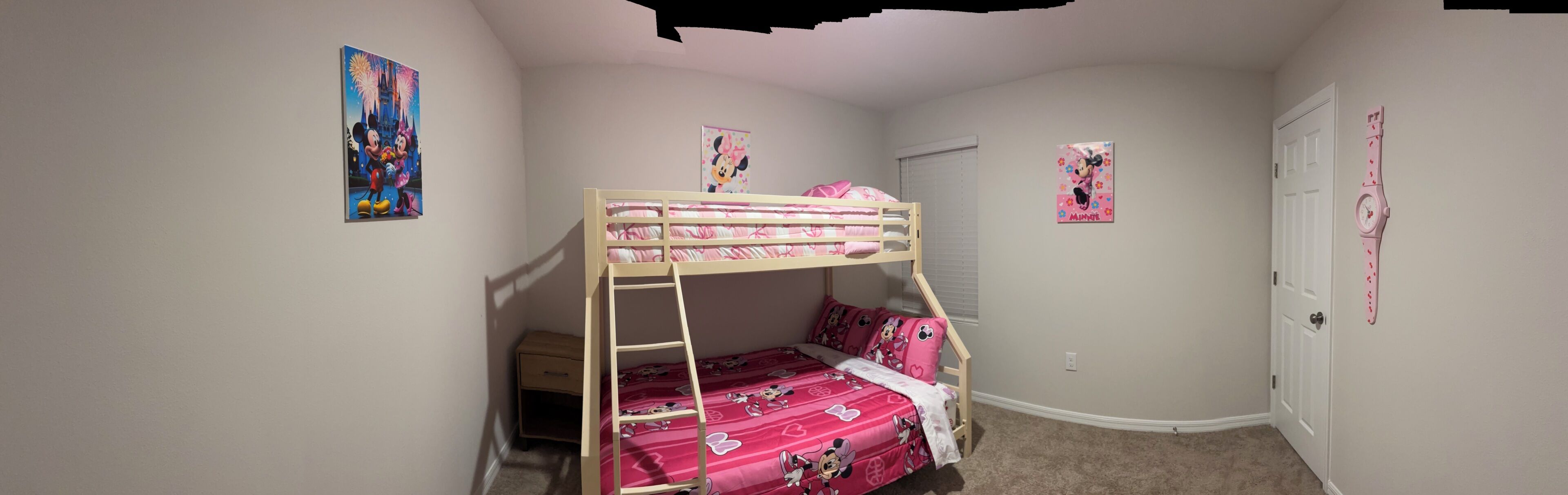 A child's bedroom with bunk beds, a ladder, and Minnie Mouse themed decorations.