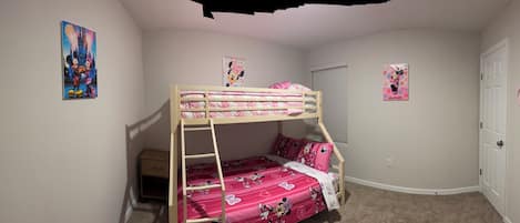 A child's bedroom with bunk beds, a ladder, and Minnie Mouse themed decorations.