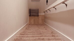 A carpeted staircase with a handrail, a door, and a window with blinds. - Spacious 5 bedroom in Haines city, Florida for families sleeping up to 12 guests (Haines City)