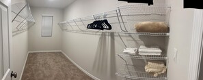 Ein Eckschrank mit Drahtregalen, einem beigen Teppich und einer weißen Tür.