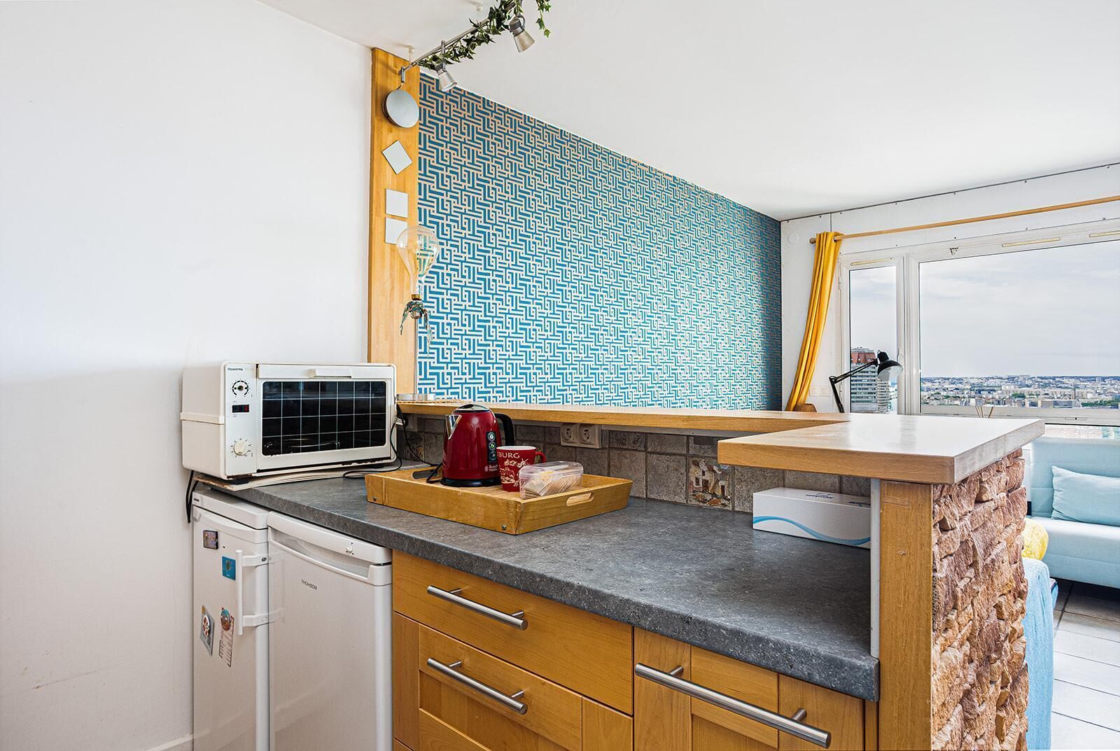 Una cocina moderna con microondas integrado, cafetera y ventana con vista a la ciudad.