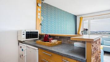 Una cocina moderna con microondas integrado, cafetera y ventana con vista a la ciudad.