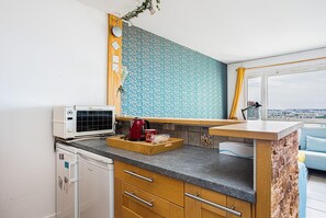 Una cocina moderna con microondas integrado, cafetera y ventana con vista a la ciudad.