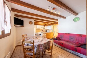 Un comedor con una mesa, sillas y un televisor en la pared.