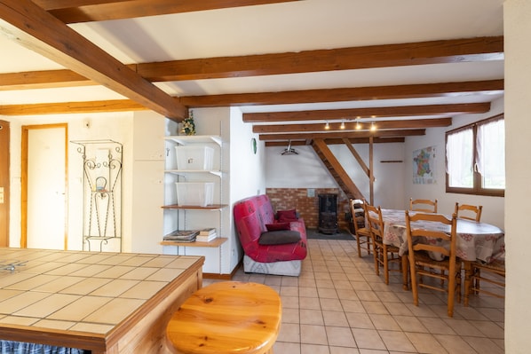 A cozy room with a wooden bench, a dining table with chairs, a fireplace, and a staircase leading to an upper level.