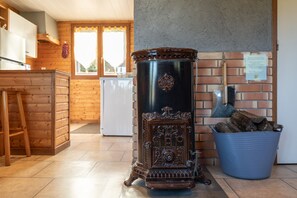 A kitchen with a stove, wooden cabinets, a blue bucket, and a brick wall.