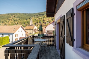 A balcony with a table and chairs, overlooking a village with traditional buildings and a church.