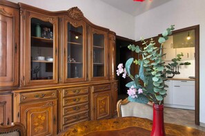 Ein Essbereich mit einem Holzkabinett, einem Tisch und einer roten Vase mit Blumen.