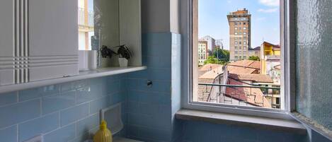 Ein Badezimmer mit Fenster, Waschbecken, Spiegel und Heizkörper.