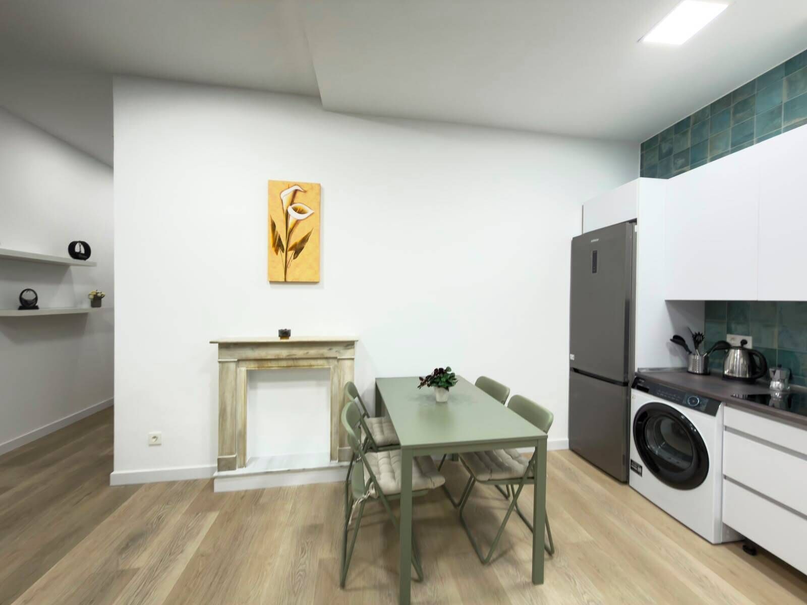 Una cocina moderna con mesa de comedor, sillas, lavadora integrada y chimenea.