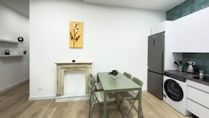 A modern kitchen with a dining table, chairs, a built-in washing machine, and a fireplace. - Habitaciones Nuevo Toledo (Madrid)