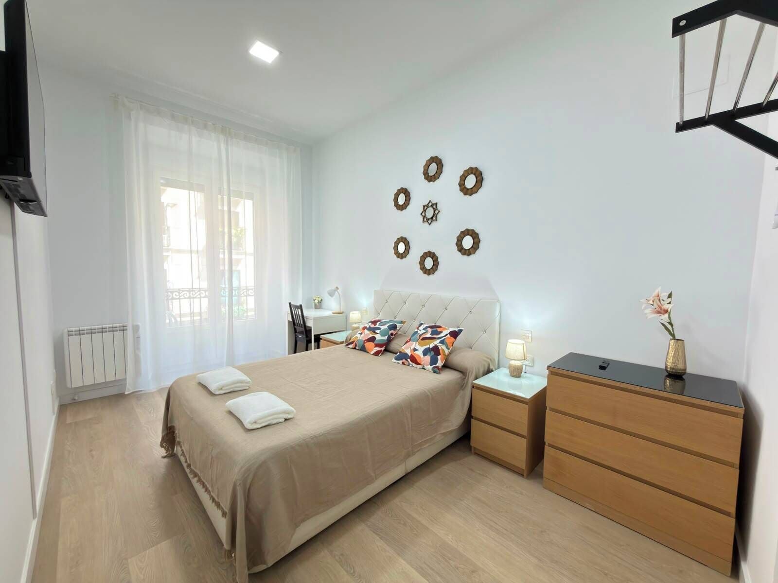 A hotel room with a bed, bedside tables, a dresser, and decorative wall art.