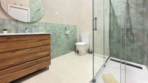 A modern bathroom with a glass-enclosed shower, a wooden vanity, and a toilet. - Habitaciones Nuevo Toledo (Madrid)