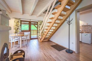 Un loft moderno con una escalera de madera, un comedor con una computadora portátil y una cocina con refrigerador.
