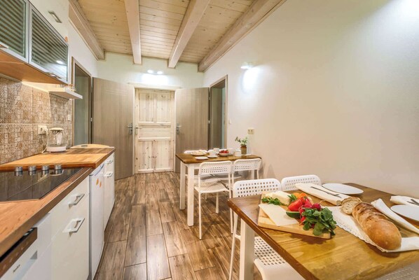 A compact kitchen with a wooden countertop, white cabinets, and a dining area with a wooden table and white chairs.