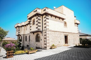 Un edificio storico con facciata in pietra, finestre ad arco e un piccolo ingresso con la scritta 'LA VITA STONE'.