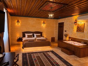 Habitación de hotel con una cama grande, techo de madera, pared de piedra, bañera y alfombra grande.