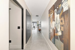 Ein Flur mit modernem Design, der eine Tür, eine Leuchte und ein großes abstraktes Gemälde an der Wand zeigt.