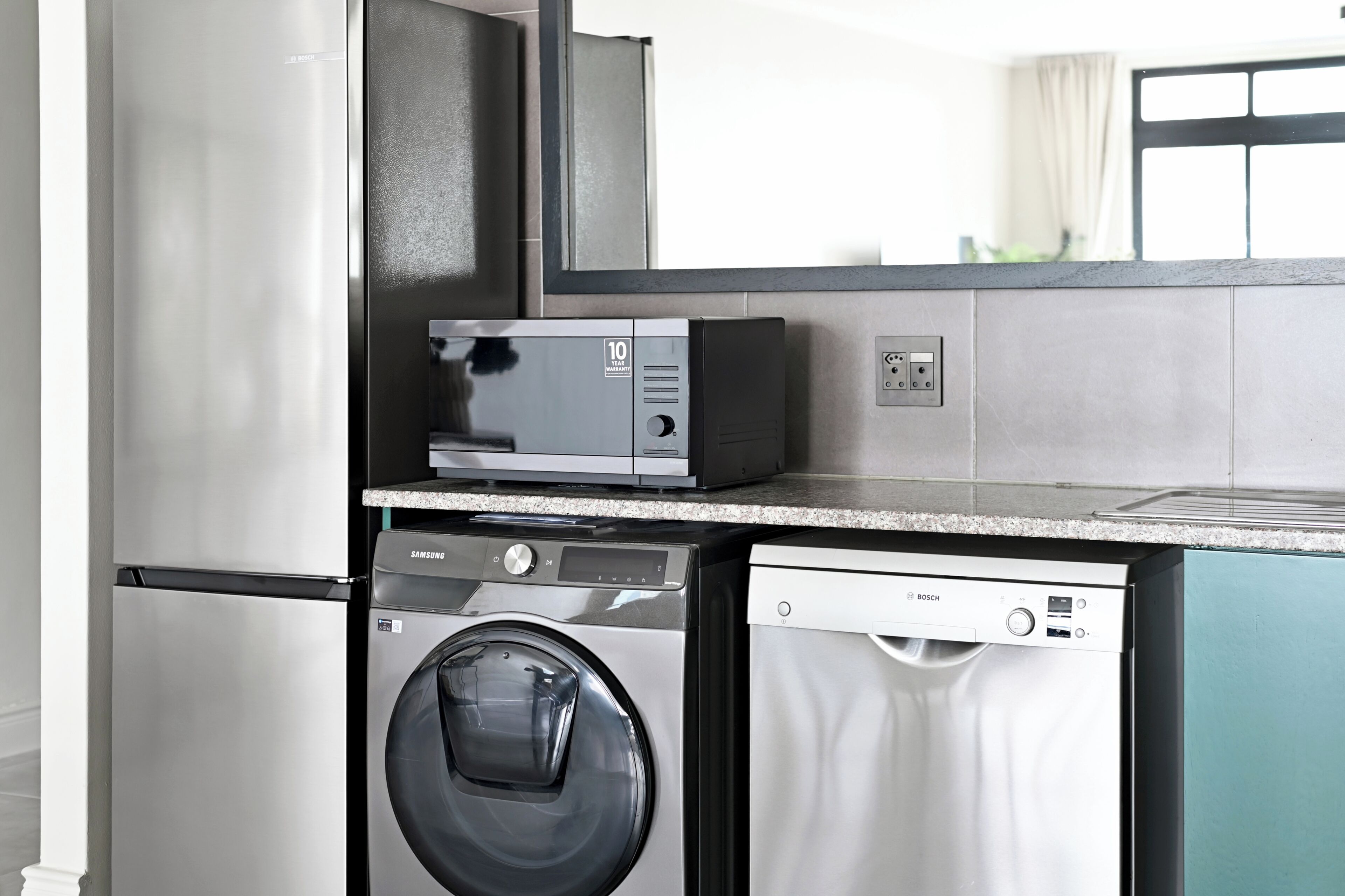 A compact kitchen with a washing machine, dishwasher, and microwave.