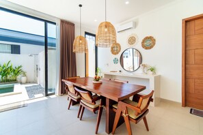 A modern dining area with a wooden table, woven chairs, and pendant lighting. - 2-Min Walk to Seseh Beach • 2BR Private Pool Villa with Rooftop Sea View (Badung)