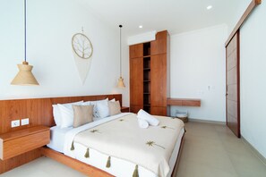 A modern bedroom with a wooden headboard, a bed with white bedding, two bedside tables, a hanging light fixture, and a wardrobe. - 2-Min Walk to Seseh Beach • 2BR Private Pool Villa with Rooftop Sea View (Badung)