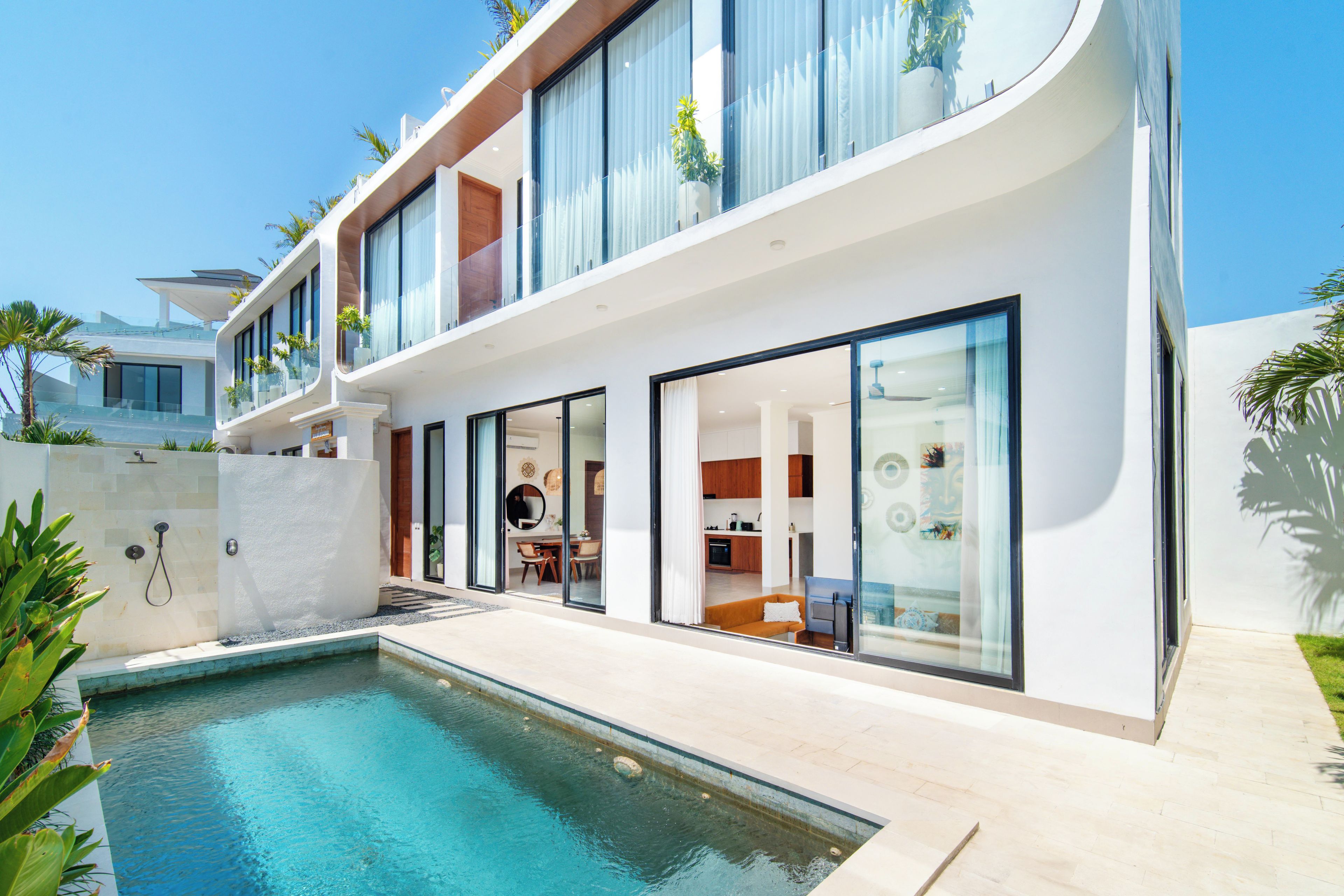 Une maison moderne à deux étages, dotée d’une piscine, de grandes fenêtres et d’un balcon.