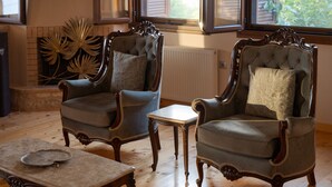 A room with two upholstered armchairs, a small table, and a decorative wall piece. - Pirgos Petropoulea (Agios Nikon)