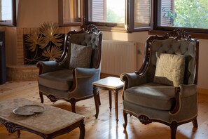 Une pièce comprenant deux fauteuils rembourrés, une petite table et un élément décoratif mural.