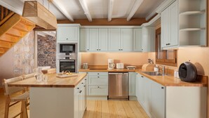 Una cocina moderna con armarios azul claro, una isla de madera, una pared de piedra y una lámpara colgante.