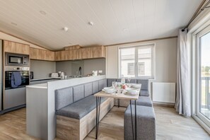 A modern kitchen with built-in appliances, a central island with seating, and large windows providing natural light. - Lodge No 173 | Hot Tub | Stewart's Resort Cameron (Cameron)