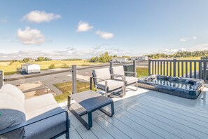 A deck with outdoor seating, a hot tub, and a view of a rural landscape. - Lodge No 173 | Hot Tub | Stewart's Resort Cameron (Cameron)